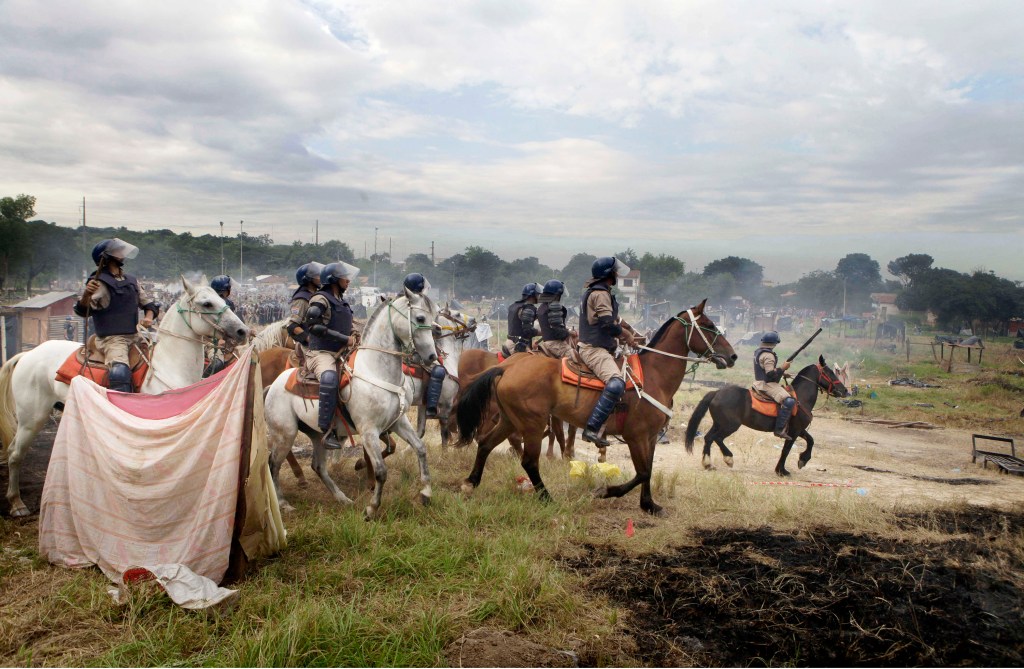 Policias antimotines cabalgan luego de desalojar ocupantes de terrenos municipales en Asuncion, Paraguay, 6 de diciembre de 2011. Mas de 400 familias fueron expulsadas. (AP Photo/Jorge Saenz)